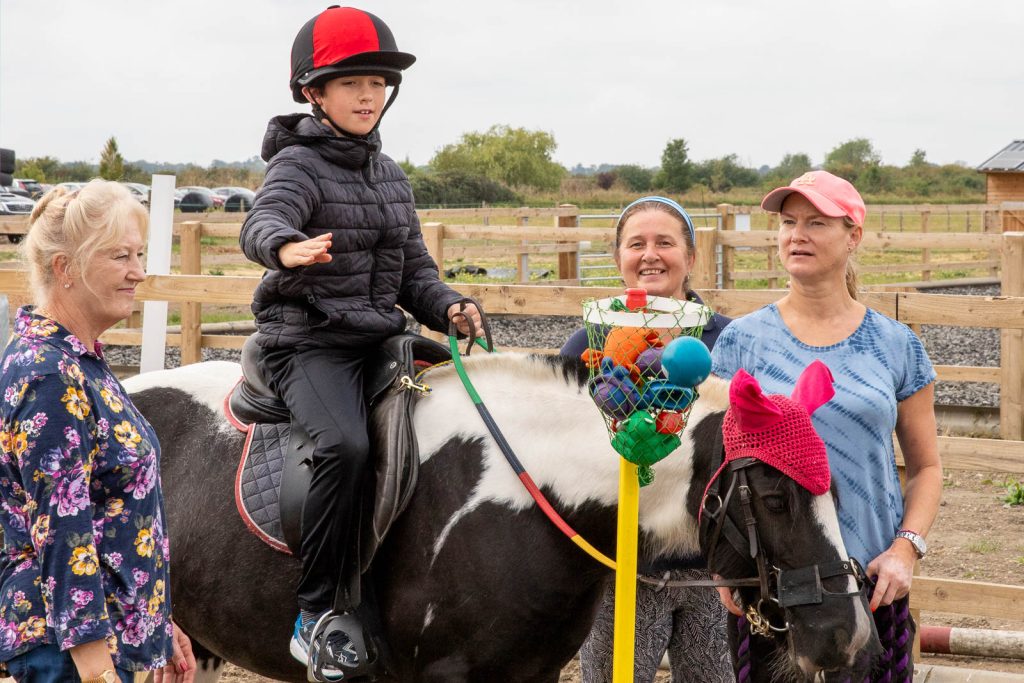 Young rider on a pony supported by volunteer helpers