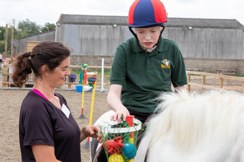 Young rider on a pony being supported by a volunteer